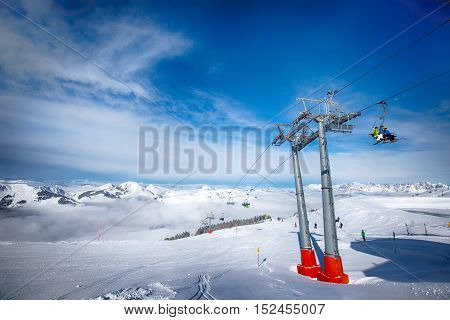 KITZBUEHEL AUSTRIA February 17 2016 - Skiers on ski lift enjoying the view to foggy Alps in Austria and beautiful snowy country panorama in famous Kitzbuehel mountain ski resort