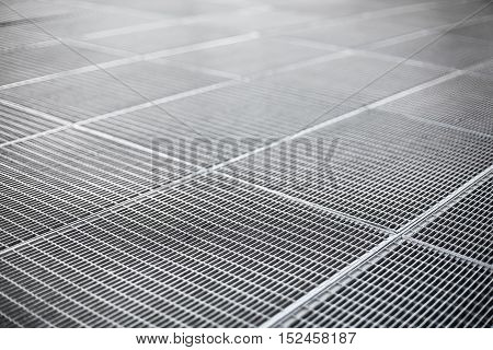 Gray color metal ventilation grille on a sidewalk with shallow depth of field