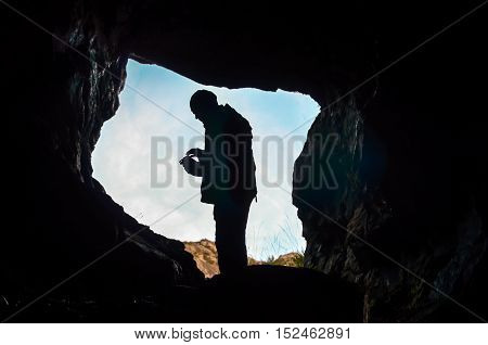 dark cave with man silhouette and water