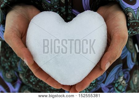 Snow on the palms of the hands in the form of heart
