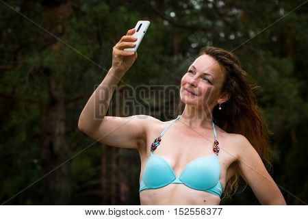 Girl In Bathing Suit In The Forest And Cell Phone