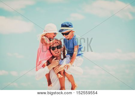 appy father with two kids on shoulders at sky, happy family