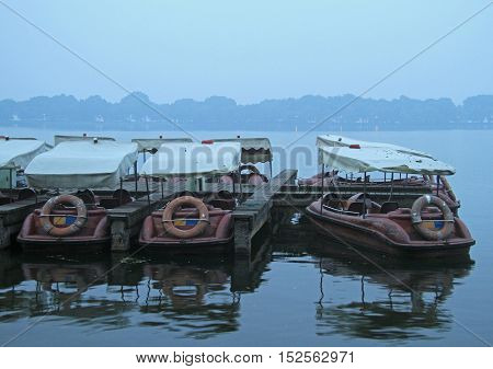 Chinese recreation boats are moored on the West Lake coast. Famous park in Hangzhou city China