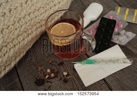 pills, thermometer, medical tea with lemon. a cold or sickness in the winter or fall.