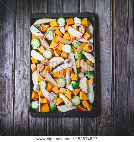 Roasted vegetables on a baking sheet: sweet potato, butternut squash, brussels sprouts, apple, pecans and pear. Toning. Healthy eating concept.