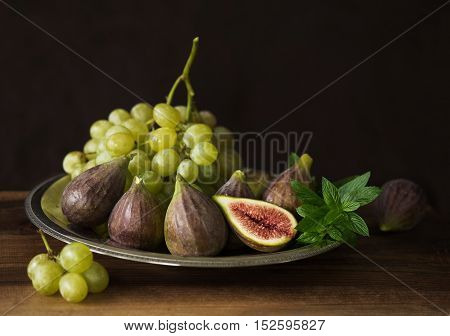 Fresh fruit: figs, grapes and mint leaves on a wooden table