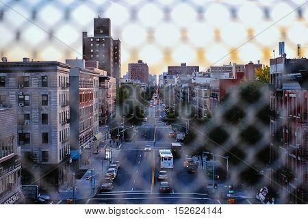 through the fence view of a busy street in upper manhattan