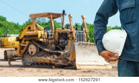 The engineering and safety helmets stood on the details of Closeup skid steer loader excavator at road construction work