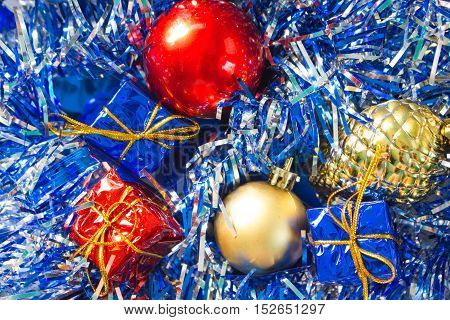 Christmas ornament closeup photo. Red and gold ball. Golden pine. Blue and red wrapped gifts. Sparkling ribbon on background. Picture for New Year greeting card seasonal holiday banner template