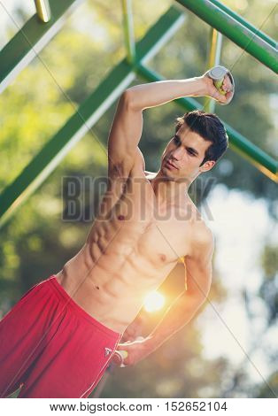 Well built muscular man doing a physical exercise outdoors