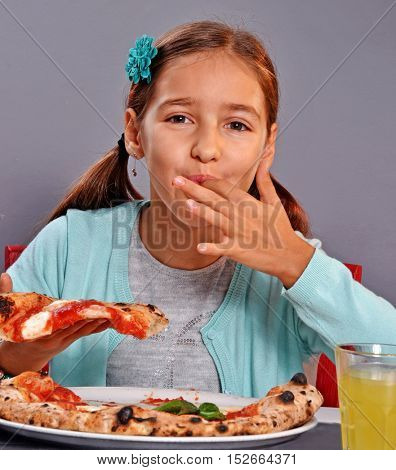 Hungry little girl sucking finger while eat margarita pizza in a restaurant.