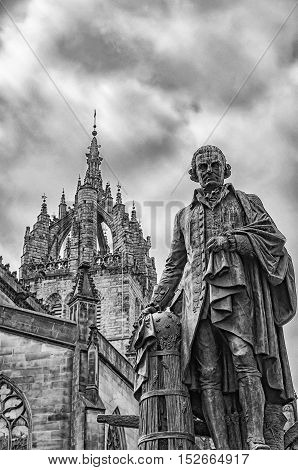 Statue of economist Adam Smith on the Royal Mile in Edinburgh capital of Scotland with St Giles cathedral in the background.