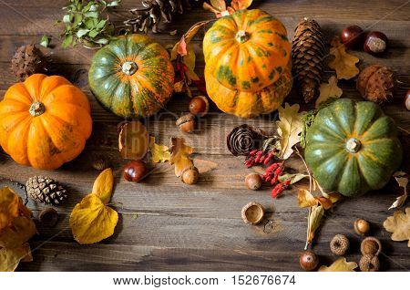 Autumn decorative pumpkins, fall leaves on a rustic wooden background, natural fall style decorations. Natural plenteous border background vintage mock up. Top view point.