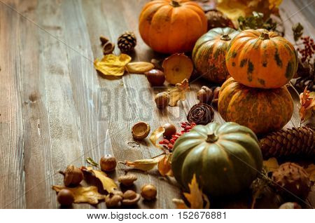 Autumn decorative pumpkins, fall leaves on a rustic wooden background, natural fall style decorations. Natural plenteous border background vintage mock up.