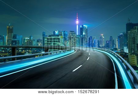 Blue neon light highway overpass motion blur with city skyline background night scene .