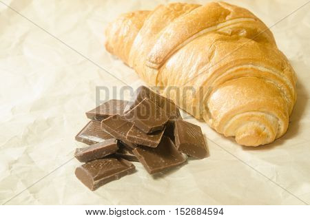 Tiles chocolate with croissant on white paper