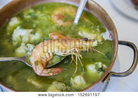 Arroz de Tamboril or soupy seafood rice portuguese recipe. Spoon holding a prawn