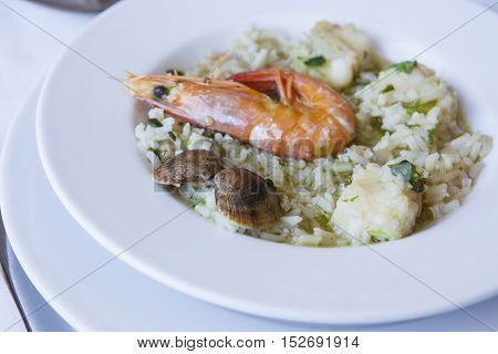 Arroz de Tamboril or soupy seafood rice on plate. Portuguese recipe