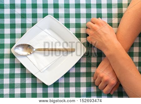 Empty Square Plate With Silver Spoon, Crossed Human Hands.