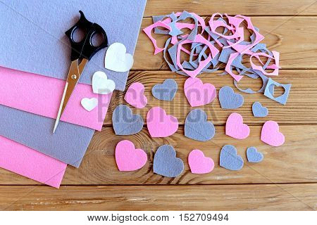 Hearts cut from felt, felt sheets set, felt scraps, paper patterns, scissors on wooden background. How to cut different hearts from felt. Children development of fine motor skills