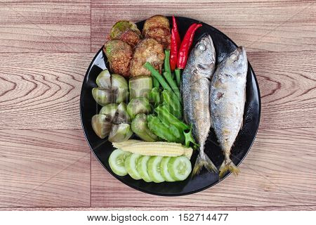 Ready side dish served  for Thai spicy sour dip   as deep fired mackarels,boiled long-eggplant,lentils,winged bean ,red hot chili pepper and sliced cucumber on wood.  Have text space for fillin.