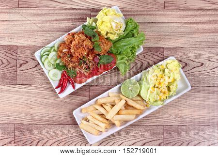 Spicy fried chicken salad (Yum Kai Zap in Thai) as spicy chicken salad,chili,tomato,red onion,roasted rice,dried chili ,Chinese cabbage,lettuce,peppermint ,cucumber and green lemon juice served with mixed vegetables salad and french fires.