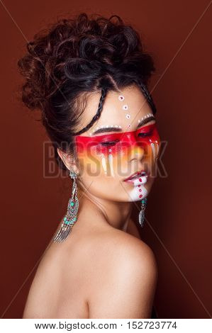 Beautiful squaw in ethnic jewelry . Close up portrait. Native american costume. Portrait of a woman with a painted face. Creative makeup and bright style.