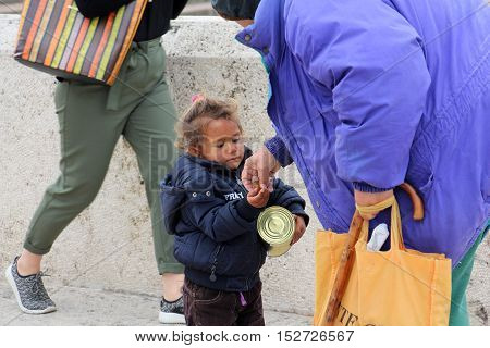 SKOPJE MACEDONIA - OCTOBER 18  2016:Older woman gives money to cute beggar girl downtown of Skopjecapital of Macedonia
