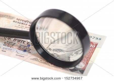 Indian Currency Rupee Note with magnifying glass isolated on white background