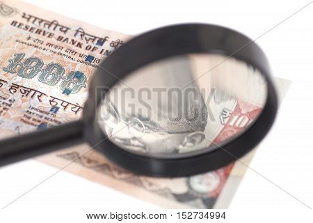 Indian Currency Rupee Note with magnifying glass isolated on white background