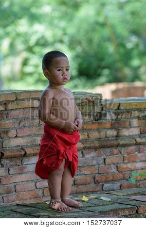 Asian Thai boy look and smile he dress thai local dress with saliva on his neck and breast.