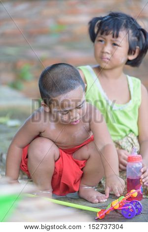 little asian boy playing toy and his sister sitting backside him.They all derssing in Thai local dress.joyful