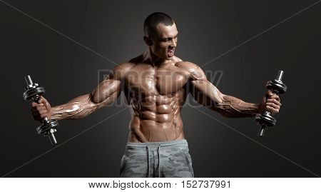 Muscular athletic bodybuilder model posing after exercises in gym