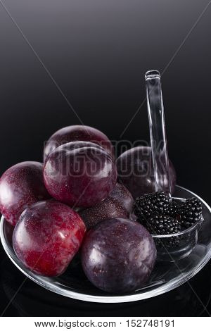 Plums and blackberries in transparent dipper to the Christmas table