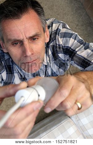 Man Removing An Old-fashioned Inefficient Tungsten Incandescent Light Bulb