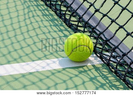 Tennis ball on green tennis court with net