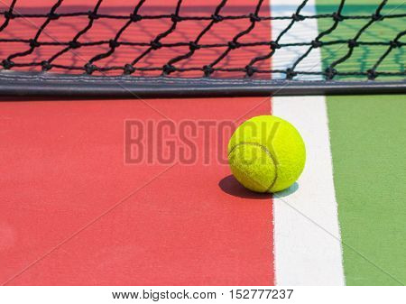 Tennis ball on green tennis court and net