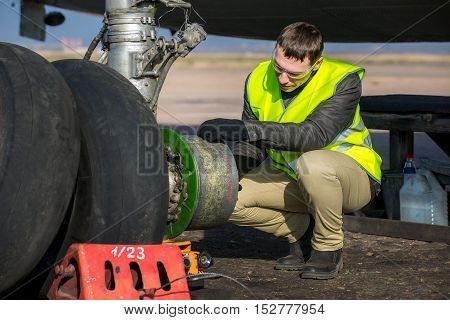 Male mechanic fixing airplane's wheels at airport