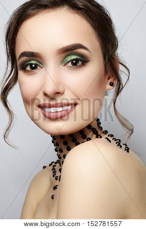 Elegant young lady with evening smart make up and beads on her neck. Make-up of woman eye with khaki eyeshadow. Beauty portrait of a girl model with make-up green eyes. Creative Professional makeup.