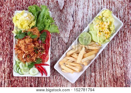 Spicy fried chicken salad (Yum Kai Zap in Thai) served mixed vegetables salad and french fires.