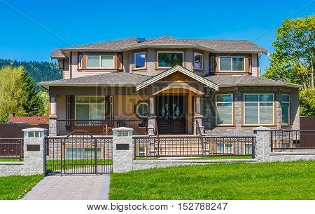 Luxury residential house with iron fence and green lawn in front