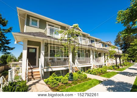 Brand new townhouses with concrete pavement in front. Front side of townhouses on sunny day in Canada.