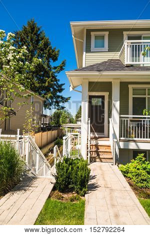Concrete pathway to the entrance of brand new townhouse on sunny day in Canada.