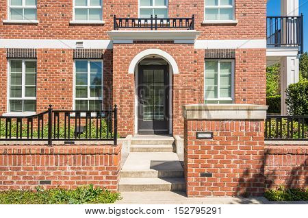 Entrance of brand new apartment building with concrete door steps and brick fence in front