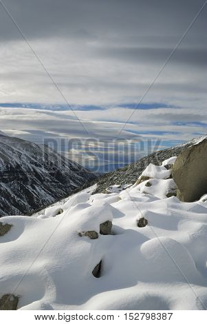 Untouched snow on the mountain slope over looking a blue lake in the distance