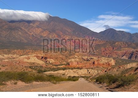 Man walking alone on a sand road with colorful background