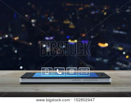 Telephone mobile phone at and email buttons on modern smart phone screen on wooden table in front of city tower background Customer support concept