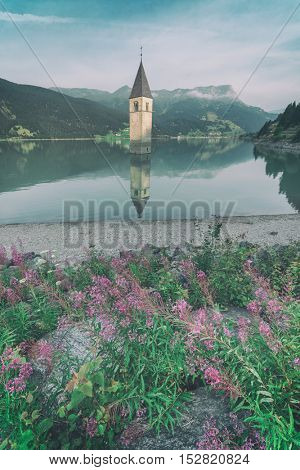 Beautiful view of the lake Resia. Famous tower in the water. Alps, Italy, Europe, toned like Instagram filter