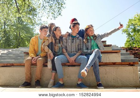 education, high school, technology and people concept - group of happy teenage students or friends taking selfie by smartphone