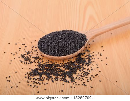 black sesame seeds in wooden spoon on wood table